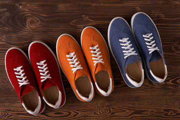 Top view of casual colorful suede trainers on wooden planks