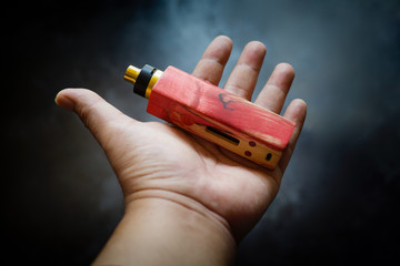 high end red and natural stabilized wood box mods with rebuildable dripping atomizer in hand on...