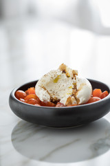 Burrata Büffelmozzarella Kugel mit Tomaten, Olivenöl und Balsamico auf schwarzen Teller