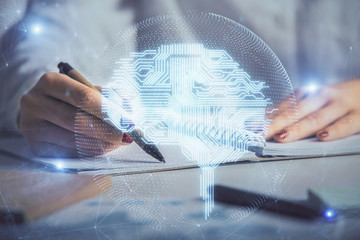 Double exposure of woman's writing hand on background with brain hologram. Concept of brainstorming.