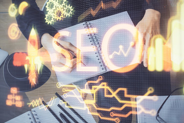 Multi exposure of woman's hands making notes with SEO icon. Concept of Search engine optimization