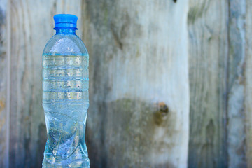 Bottle with fresh clean water on blurred wooden wall background.