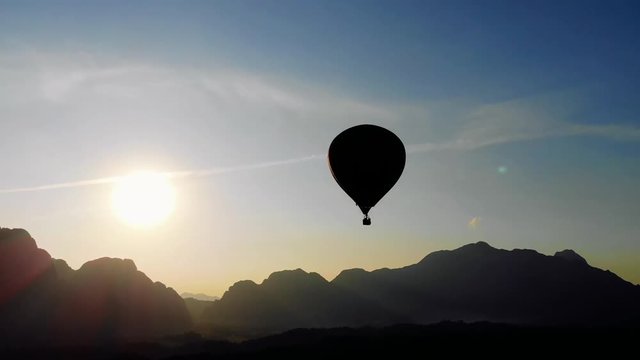 Balloon on the background of the sun at sunset. red hot-air balloon raising just in time to explore the beautiful sunset over Vang Vieng in Laos, Southeast Asia. top view, aerial view. 4K move drone