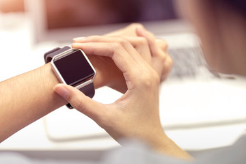 Woman hand with smart watch on wrist, wearable watch and technology computer laptop for communication, checking time.