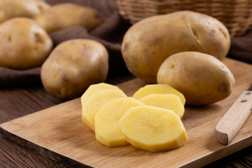 Raw potato sliced on board prepare for cooking, Fresh organic golden potatoes on wooden desk..