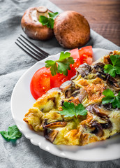 omelette with mushrooms in white plate on wooden table background