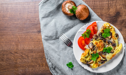 omelette with mushrooms in white plate on wooden table background