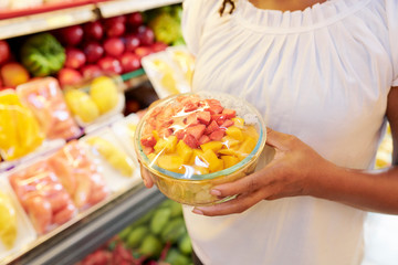 Bowl of fruit and berry salad in hands of supermarket female customer