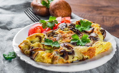 omelette with mushrooms in white plate on wooden table background
