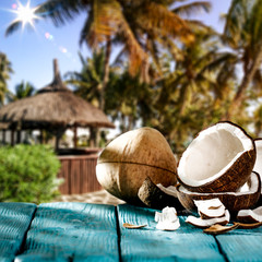 Coconuts on wooden table and summer palms. 