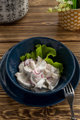 Pickled milk mushrooms with red onion and sour cream on wooden table