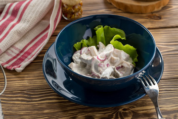 Pickled milk mushrooms with red onion and sour cream on wooden table