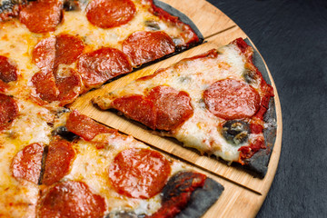 Hot big pepperoni pizza from black dough tasty.