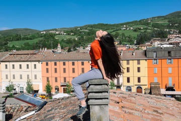 brunette with very long hair sitting on a chimney