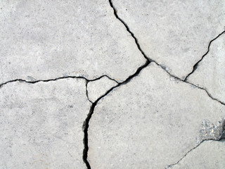 detail of fractured concrete sidewalk floor, gray grunge cement surface with large cracks,...