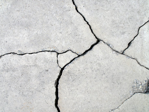 detail of fractured concrete sidewalk floor, gray grunge cement surface with large cracks, earthquake effect causes ground and building wall to damaged, abstract texture background, close up top view