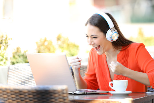 Excited woman watching and listening media on laptop
