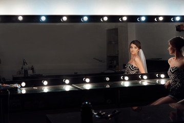 Fototapeta na wymiar stylish gorgeous bride getting makeup in the luxury beauty saloon with big mirrors and light