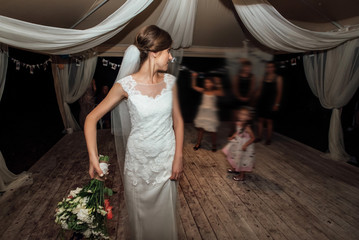 stylish happy bride throwing bouquet and having fun at the wedding reception