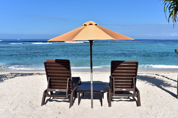 Sun umbrella and beach chairs on sandy shore near the sea in Gili Meno Island, Lombok, Indonesia