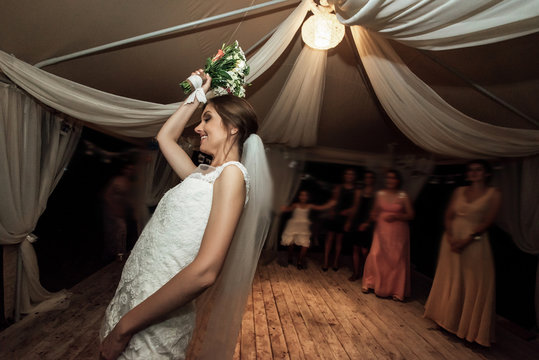 Stylish Happy Bride Throwing Bouquet And Having Fun At The Wedding Reception