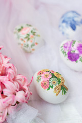 Decorated Easter eggs and flowers on white tulle background; decoupage technique