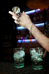 Bartender pours alcoholic drink into cocktail glass