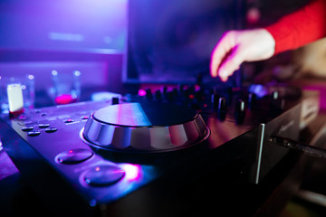 DJ mixing tracks on a mixer in a nightclub