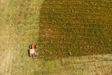 Aerial top view agriculture, tractor removes mowing green grass field