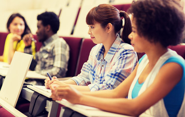 education, high school, university, learning and people concept - group of international students talking in lecture hall