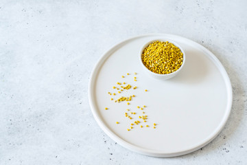 Bee pollen in a bowl on white stone background
