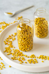 Bee pollen in glass vial on white stone background