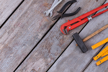 Tools for repair and construction. Folding ruler, adjustable pliers, hammer and wrenches on old woden boards. Space for text.