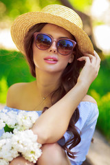 Outdoor summer portrait of young brunette woman with flowers in park