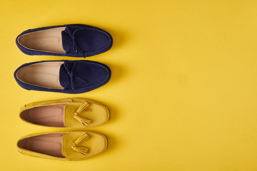 Dark blue suede man's and yellow woman's moccasins shoes over yellow background,