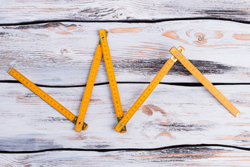 Yellow folding ruler on wooden background. Yellow meter on light wooden boards. Tool for carpenter.