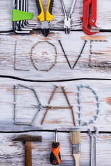 LOVE DAD text with various instruments. Inscription I Love Dad with different tools on wooden table. Fathers Day concept.