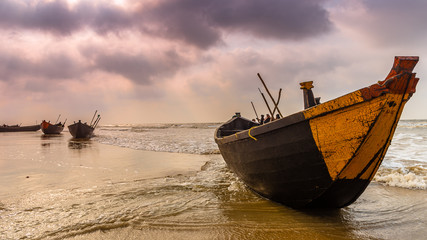 A wooden boat is anchored on the seashore.