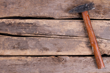 Old hammer on rustic wooden boards. Tool on old cracked wooden floor. Space for text.