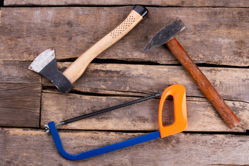 Various tools on old wooden boards. Hammer, axe and wood saw on rustic wooden planks background....