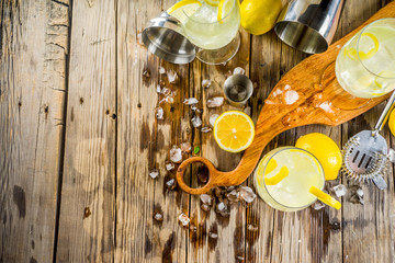 Trendy summer cold drink. St Germain French Spritz cocktail with lemon slices, old rustic wooden background copy space