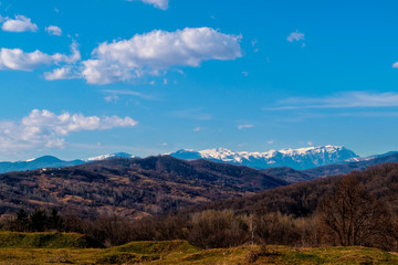 early spring hills with snow covered mountain tips in the background