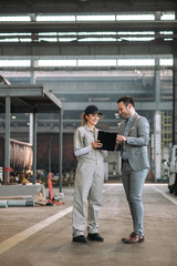 Elegant manager at heavy industry factory talking with a young female employee.