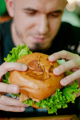 Man in a restaurant eating a hamburger, he is hungry and having a good bite. selective focus