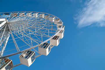 Ferris wheel on blue sky with white clouds background.
