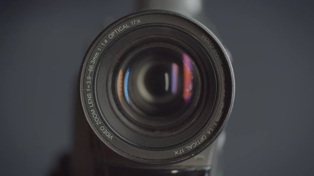 Close-up shot of the objective of videocamera with red reflections on its lens.