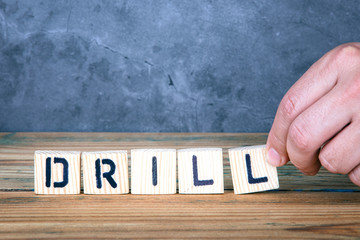 Drill - word from wooden letters on wooden table