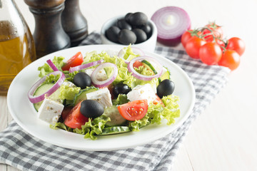 Fresh healthy salad with delicious ruccola, spinach, cabbage, arugula, feta cheese, red onion, cucumber, sesame seeds and cherry tomato on wooden background. Healthy and diet food concept.