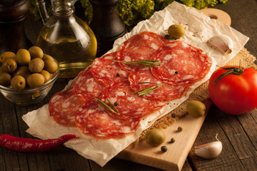 Chorizo sausage and salami, thin cut. spanish salami on the wood background with spices, paprika, pepper. Spicy food. Garlic, tomato, salad background.