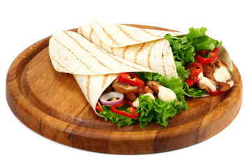 Tortilla wrap with fried chicken meat and vegetables on wooden board isolated on white background